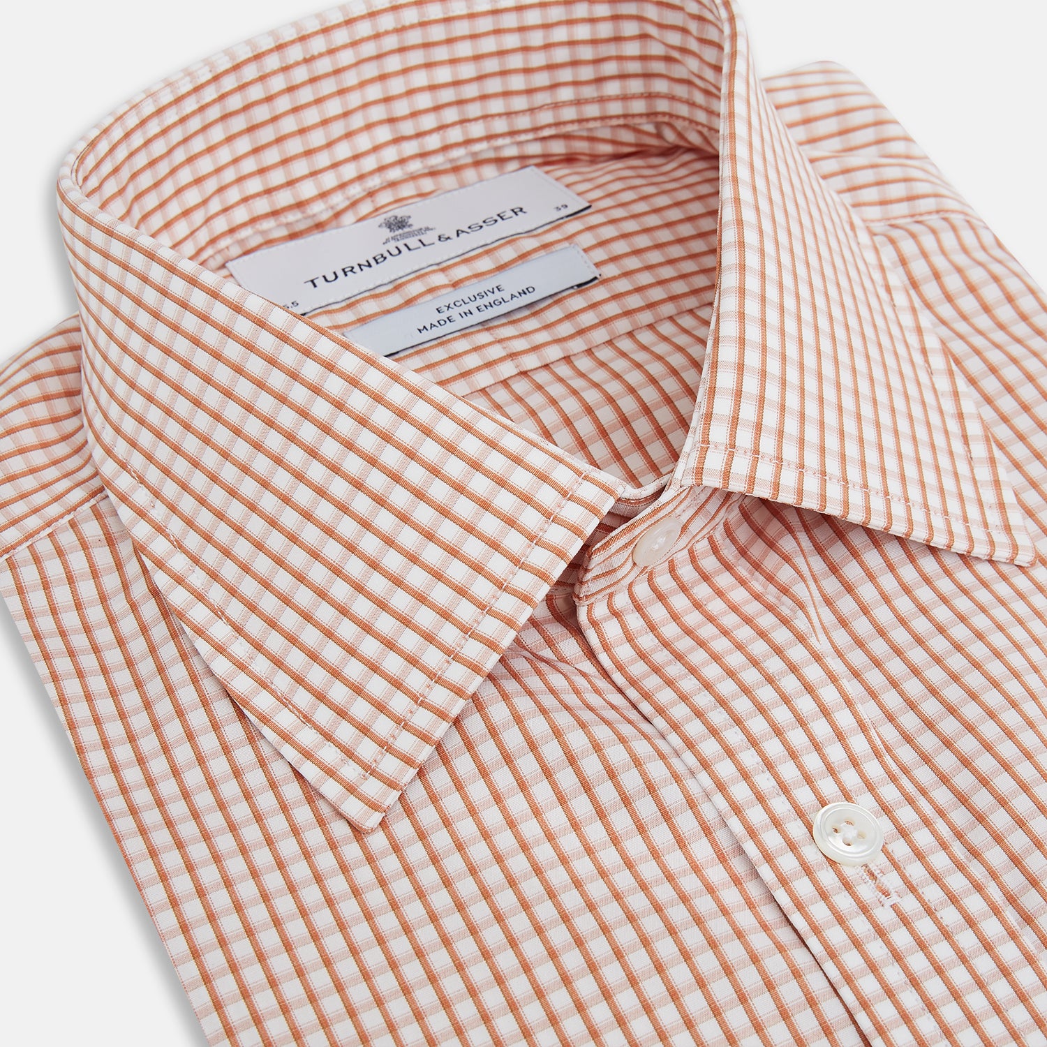 Image 2 of product The Orange Micro Shadow Check Mayfair Shirt by Turnbull & Asser features a T&A collar, button-down front, and buttoned cuffs; crafted from Italian cotton in an orange and white check pattern, laid flat on a white background.