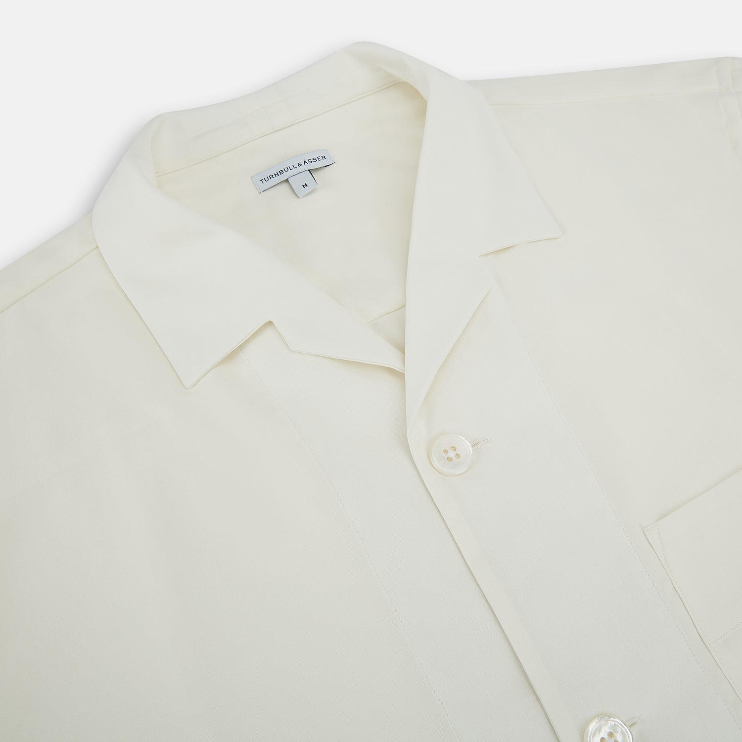 Image 2 of product The Turnbull & Asser Cream Silk Pyjama Set, shown laid flat on a white background, features a long-sleeve button-up top with a chest pocket and matching pants with an elastic drawstring waist—ideal for comfortable loungewear.