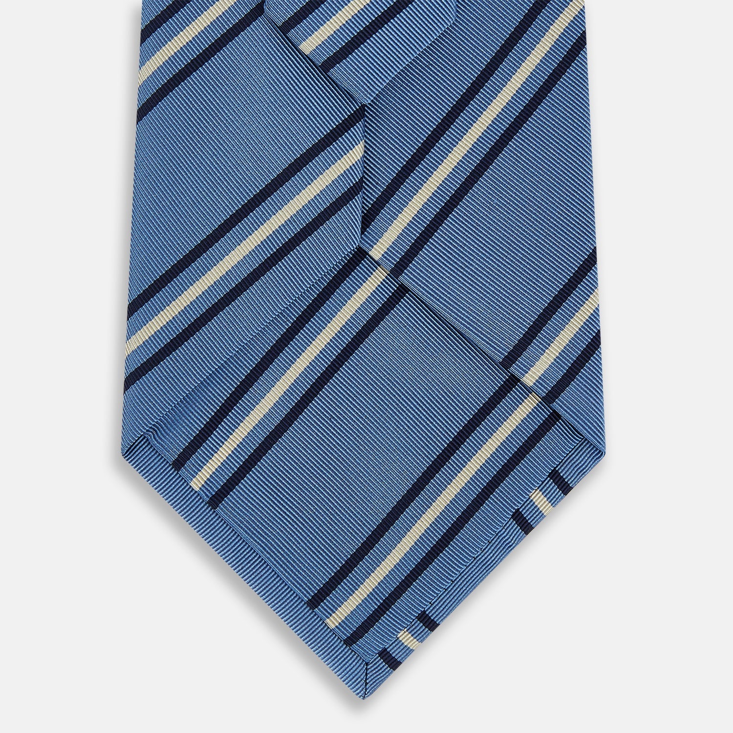 Image 3 of product The Blue Multi Stripe Silk Blend Tie by Turnbull & Asser features diagonal navy and light beige stripes, shown rolled up on a white background—a timeless formal accessory.