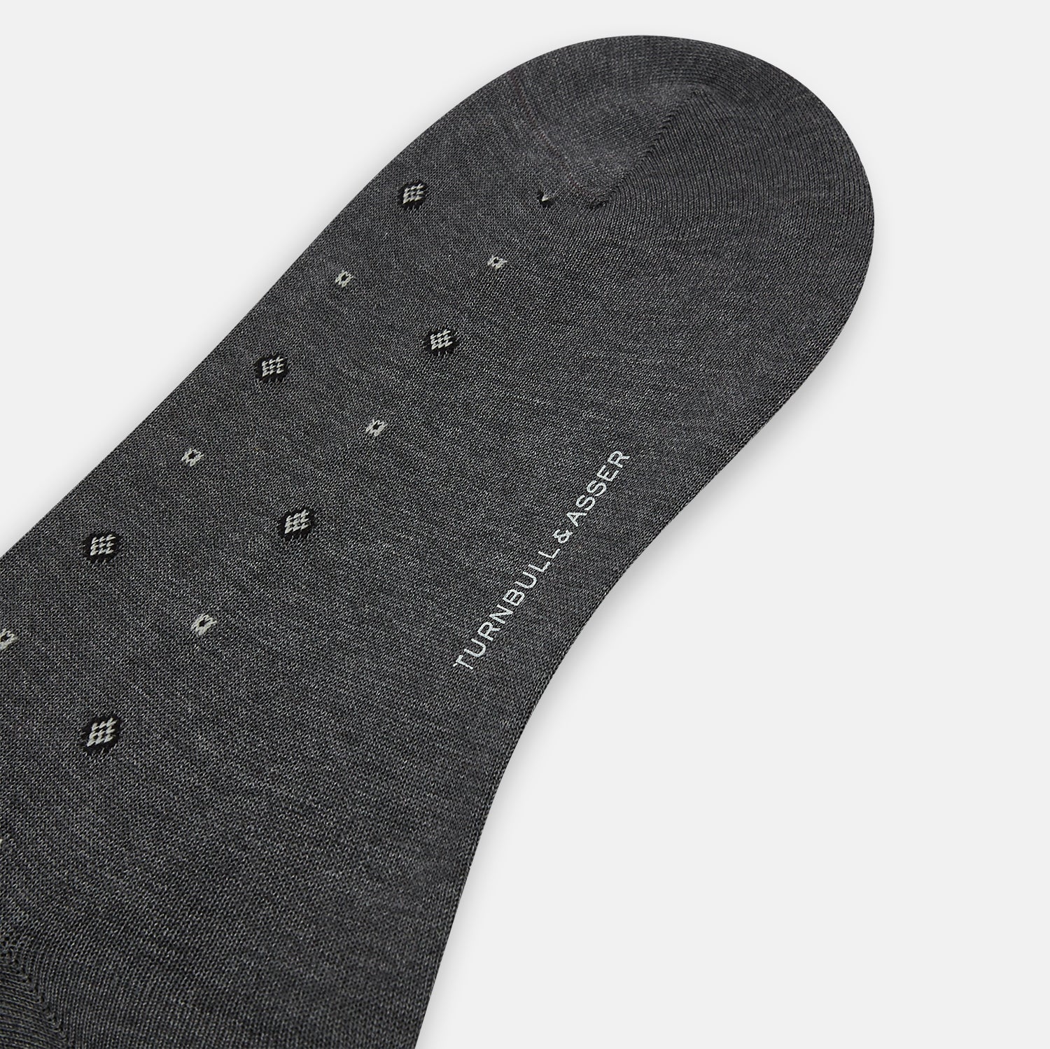 Image 3 of product The Grey Patterned Mid-Length Socks by Turnbull & Asser are crafted from soft Egyptian cotton, with a ribbed cuff and small white diamond shapes on a grey background.