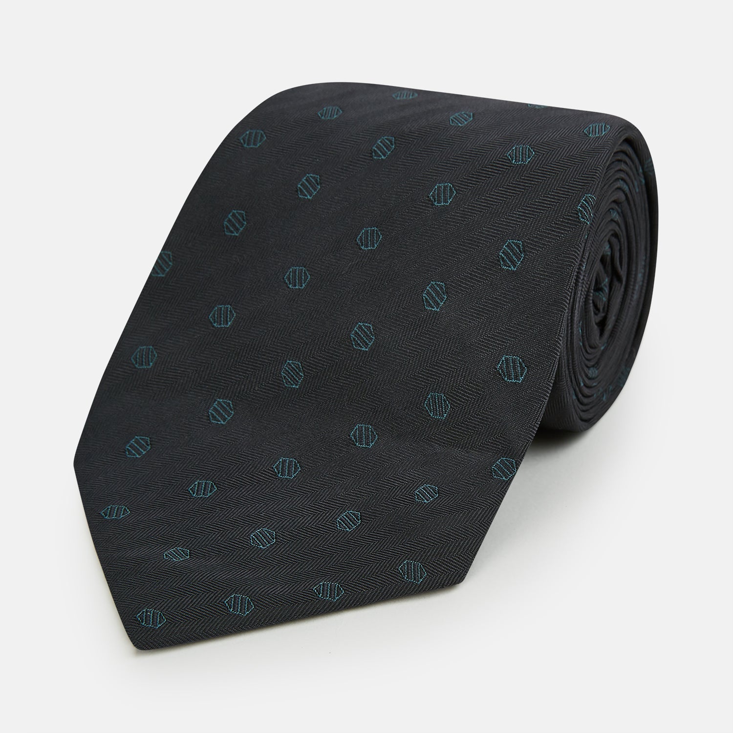 Image 1 of product The Turnbull & Asser Teal and Navy Circle Silk Tie features a subtle herringbone pattern with small repeating circle motifs, displayed neatly rolled on a white background.