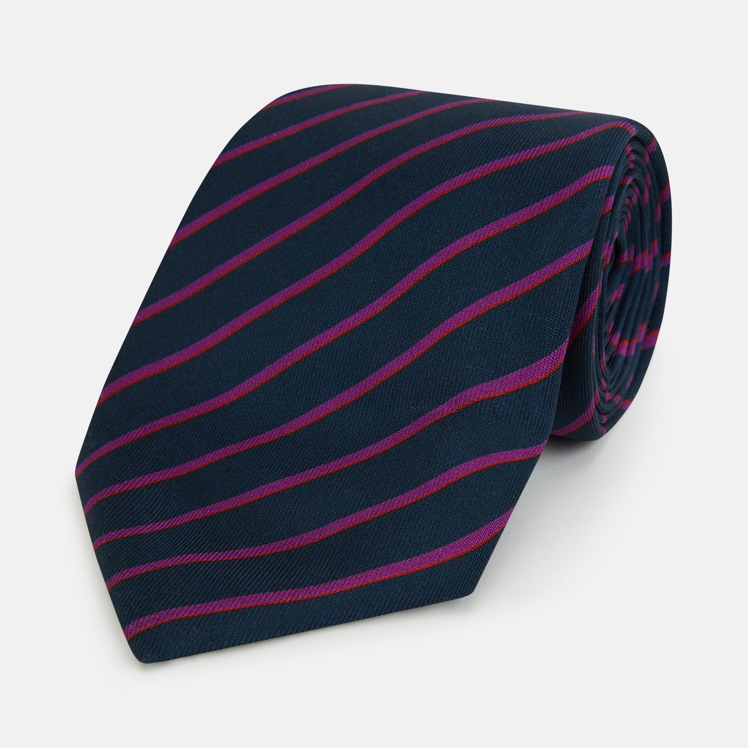 Image 1 of product The Turnbull & Asser Navy and Purple Striped Blazer Silk Tie features British craftsmanship with diagonal magenta and purple stripes, displayed neatly rolled on a white background.