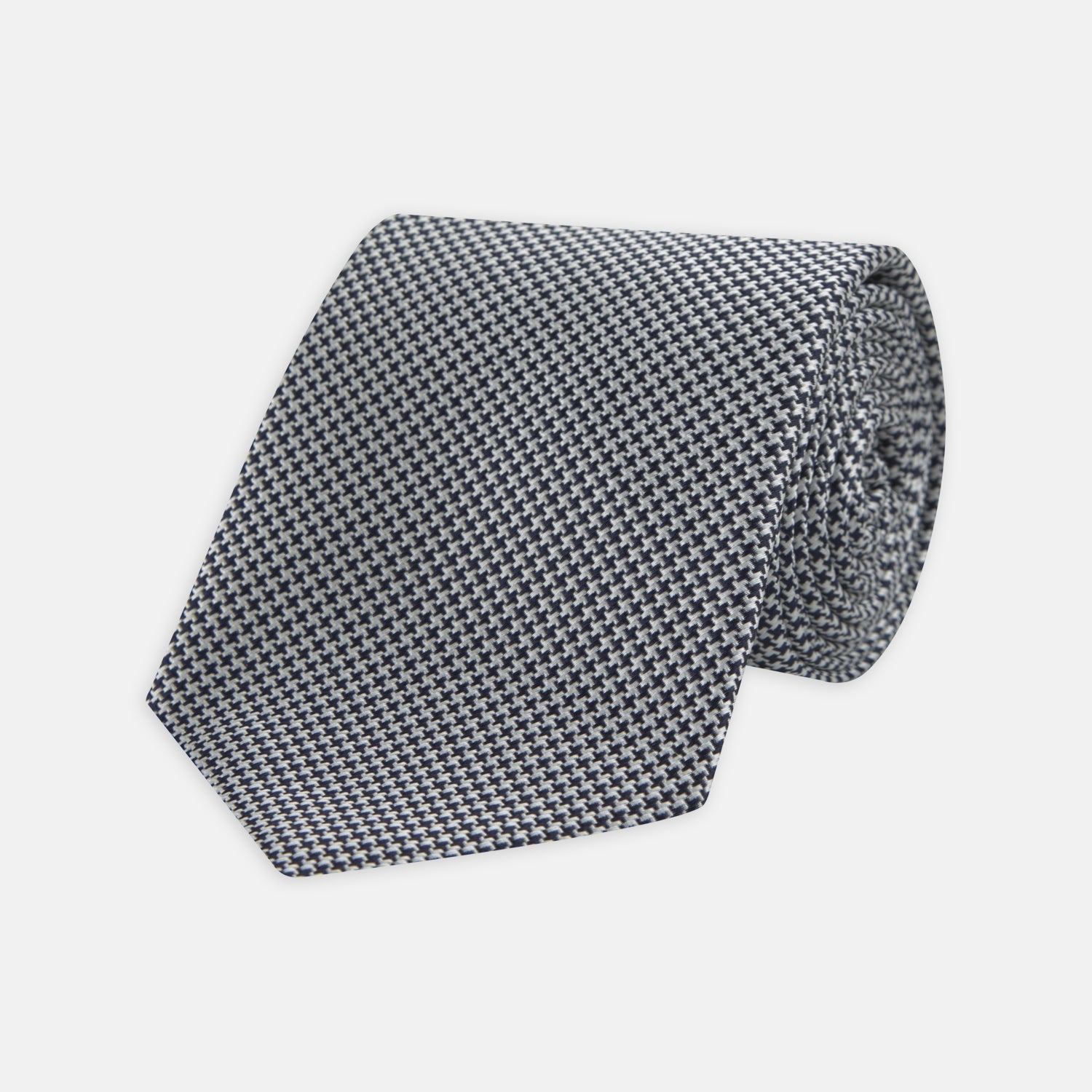 Image 1 of product The Turnbull & Asser Navy Houndstooth Silk Tie features a refined small houndstooth pattern in navy, elegantly rolled and showcased on a white background.
