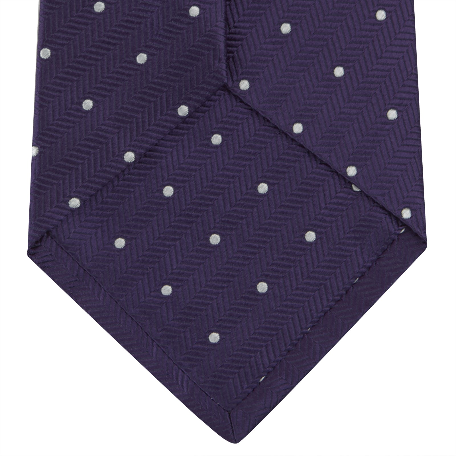 Image 4 of product The Turnbull & Asser Plum and White Small Spot Herringbone Silk Tie is shown rolled up on a plain white background, featuring a classic silk herringbone weave in plum with small white spots.