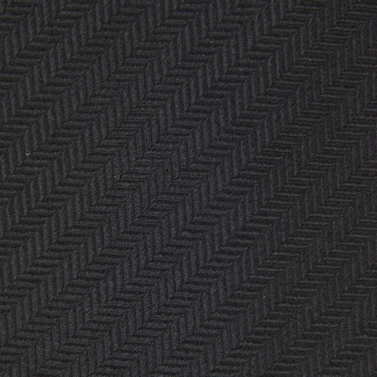 Image 3 of product The Turnbull & Asser Black Herringbone Silk Tie is rolled up and displayed on a plain white background, showcasing its classic style and subtle chevron pattern.