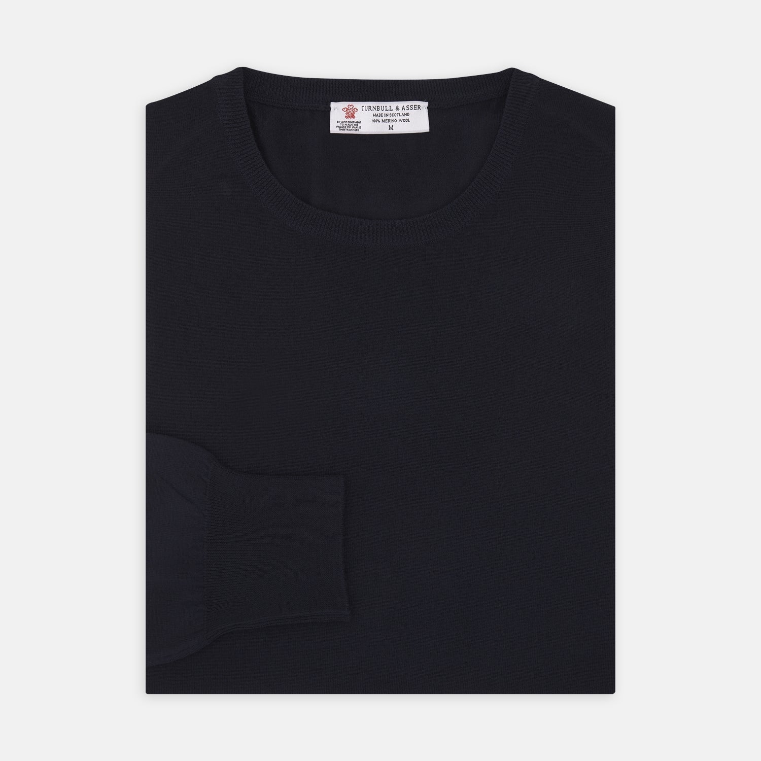 Image 1 of product A neatly folded Indigo Crew Neck Merino Wool Jumper by Turnbull & Asser, featuring a visible brand label at the collar and one sleeve tucked across the front, displayed on a white background—a versatile staple for any gentleman's wardrobe.