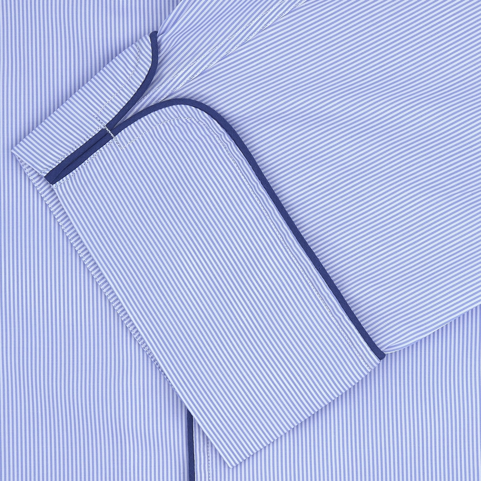 Image 2 of product The Turnbull & Asser Blue Fine Stripe Piped Sea Island Quality Cotton Pyjama Set, featuring a button-up shirt and matching nightcap, is neatly folded and displayed on a plain white background.