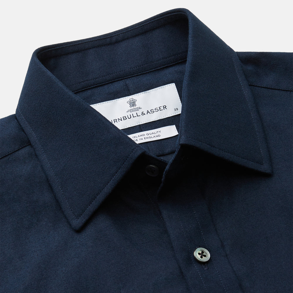 The Turnbull & Asser Navy Cotton Regular Fit Mayfair Shirt is a long-sleeved men’s formal shirt with a collar and white buttons, shown against a plain white background.