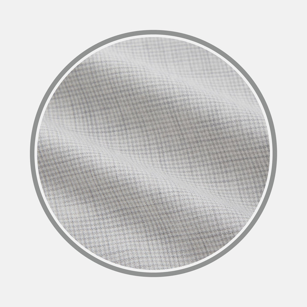 Close-up of Turnbull & Asser's NEW BESPOKE FABRIC 0124 31 in light gray with a subtle checkered pattern—ideal for a tailored shirt. Displayed within a circular frame on white, the soft fabric features gentle folds.
