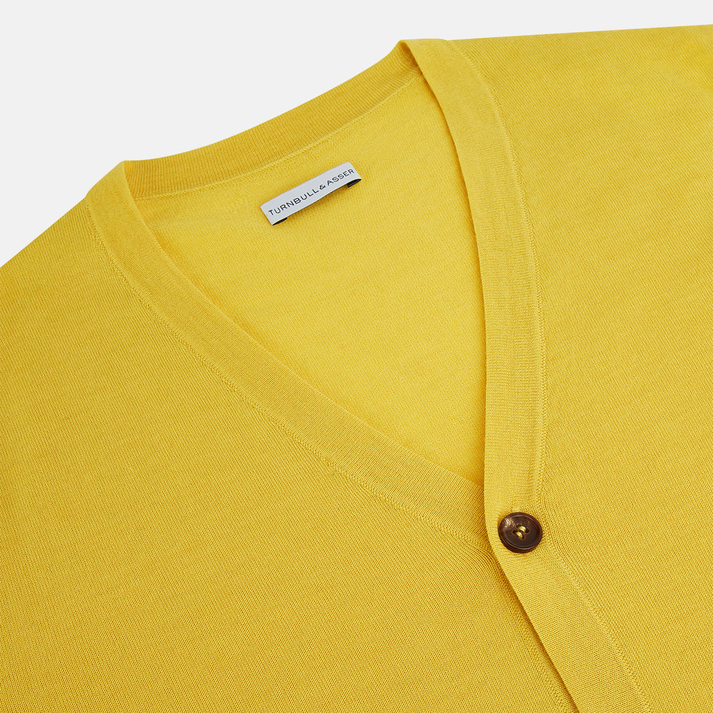 The Turnbull & Asser Canary Yellow Fine Merino V-Neck Cardigan features long sleeves, a button front with brown buttons, and ribbed cuffs and hem, displayed on a plain white background.