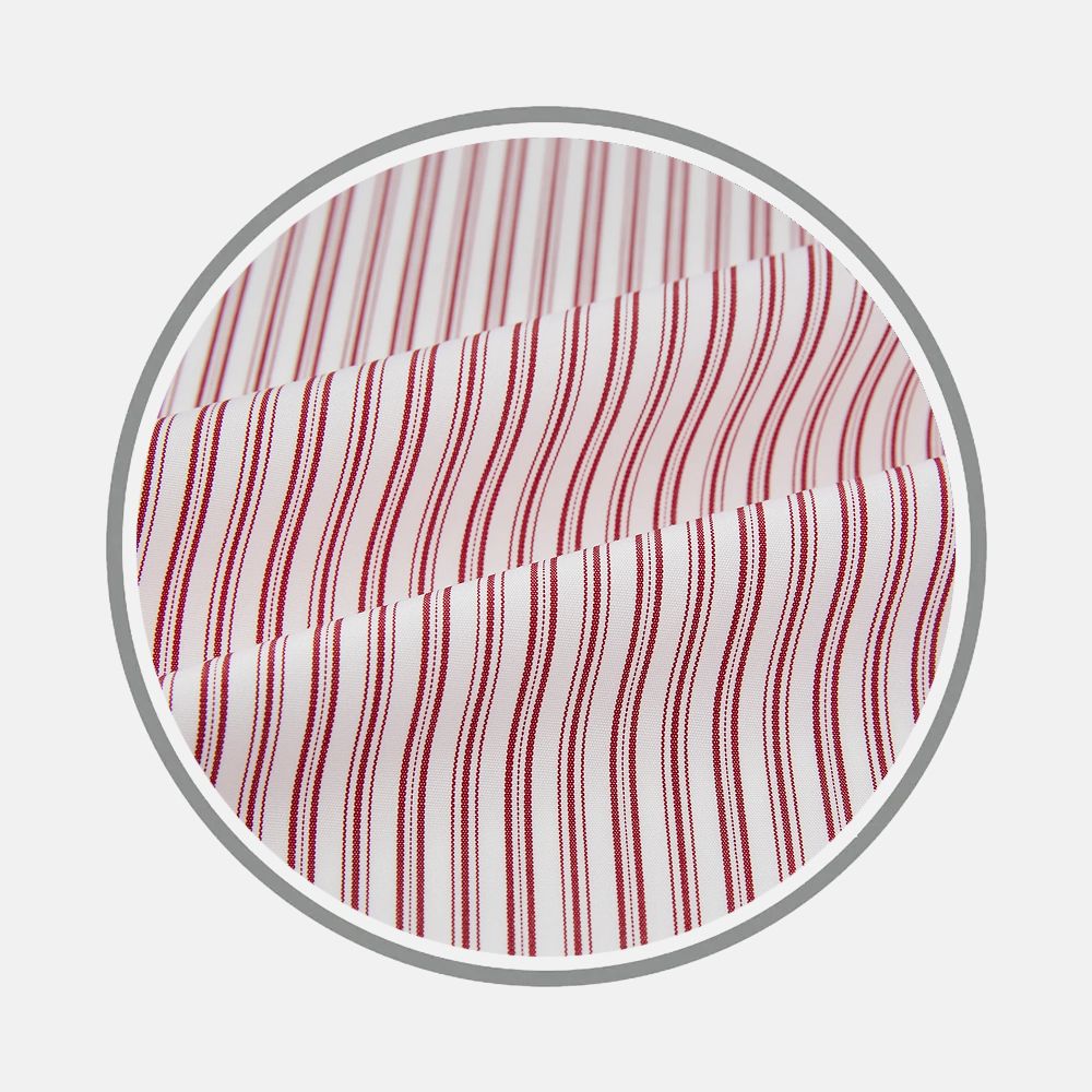 Close-up of Bespoke Fabric 73 01 by Turnbull & Asser, featuring red vertical stripes on white within a circular frame. The gentle folds showcase the fine craftsmanship typical of bespoke shirts.