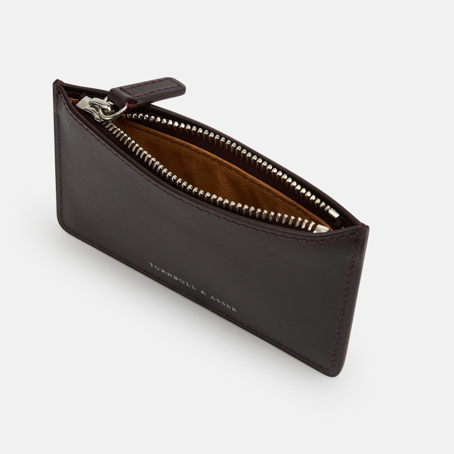 View 2 of product A Burgundy Leather Zip Wallet by Turnbull & Asser, featuring the brand's white logo near the bottom center, displayed on a plain white background.