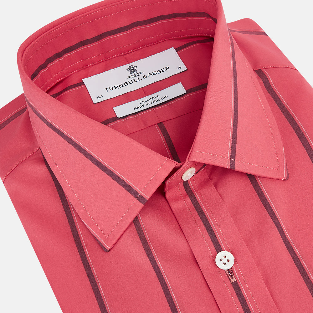 The Coral Red Track Stripe Mayfair Shirt by Turnbull & Asser features long sleeves, button-up front, a classic T&A collar, and buttoned cuffs in vibrant Italian cotton with vertical black pinstripes, shown on a plain white background.