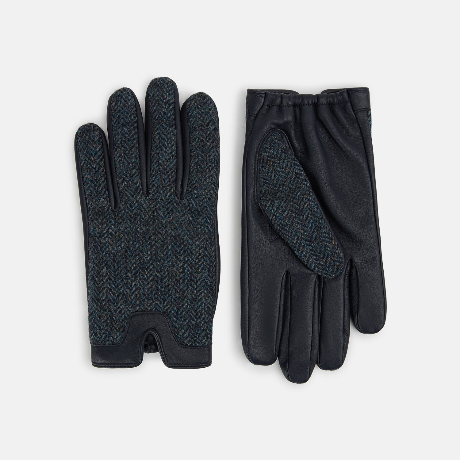 View 1 of product Turnbull & Asser Navy Herringbone Tweed Cashmere-Lined Leather Gloves are shown on a white background: one glove features dark navy herringbone tweed, the other shows a smooth black leather palm.