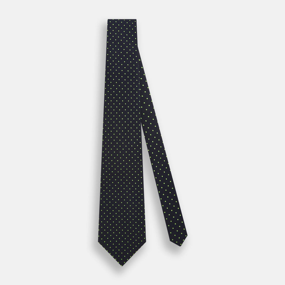 The Turnbull & Asser Green and Navy Micro Dot Silk Tie features small green dots on a navy silk background, displayed rolled up on white.