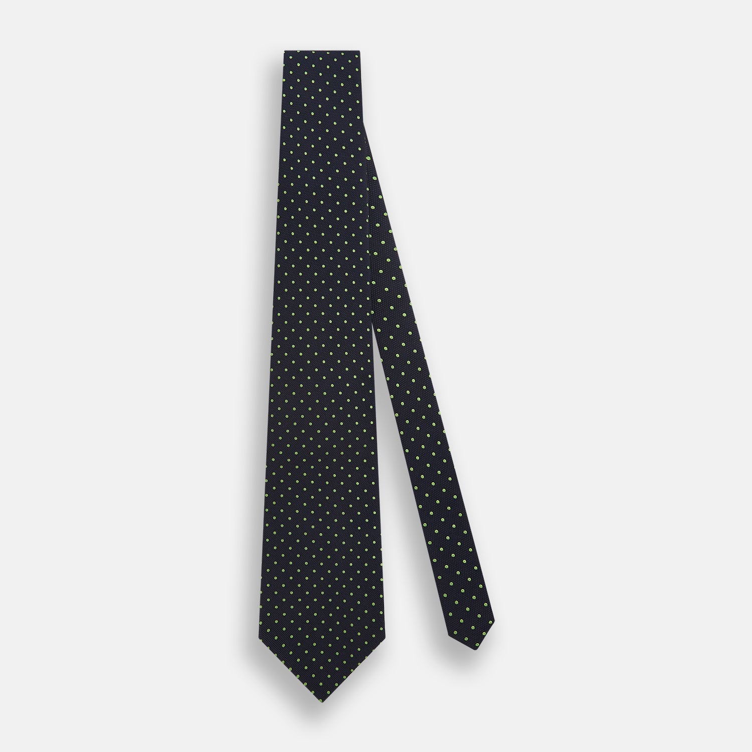 View 2 of product The Turnbull & Asser Green and Navy Micro Dot Silk Tie features small green dots on a navy silk background, displayed rolled up on white.