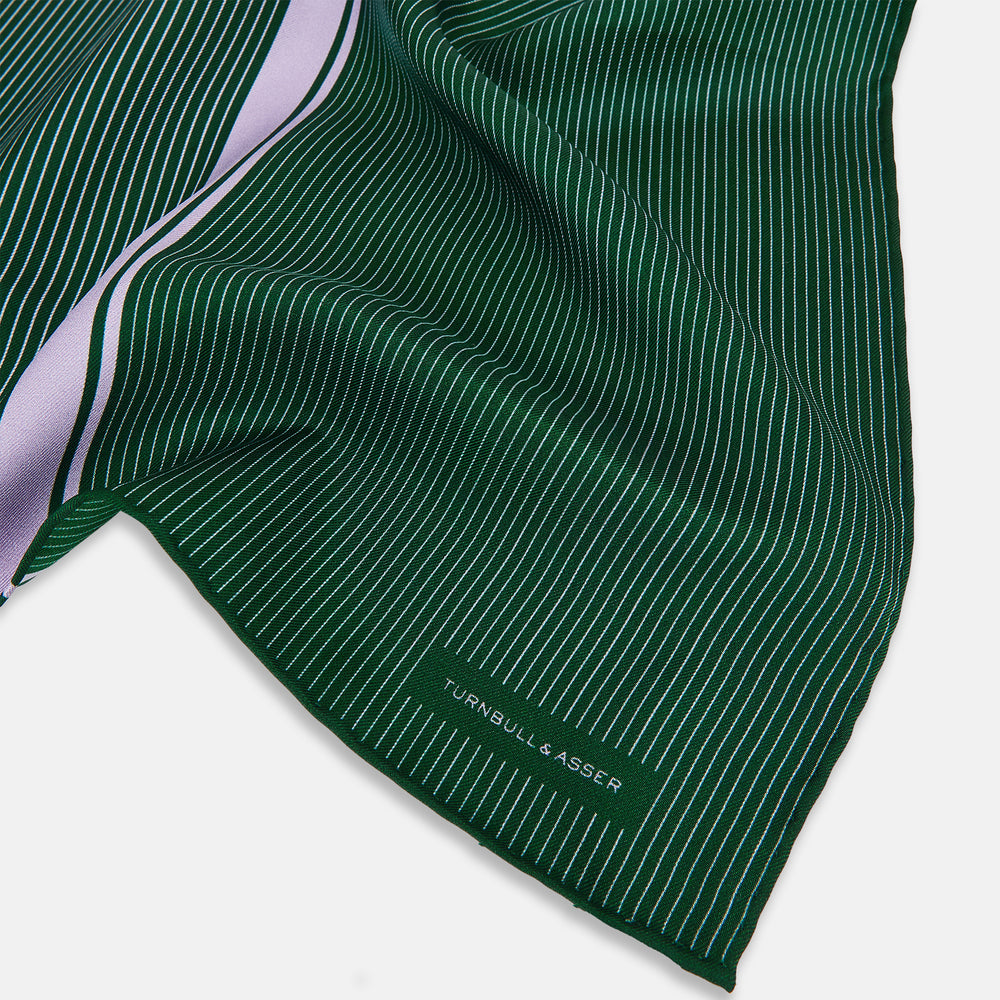 The Forest Green and Lilac Stripe Silk Pocket Square by Turnbull & Asser features thin white pinstripes, a bold light purple vertical stripe, and a visible branded label for classic British elegance. One corner is neatly folded over.