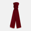View 1 of product The Burgundy Cashmere Scarf by Turnbull & Asser features a soft texture, deep red hue, and lightly frayed edges, loosely knotted and displayed on a plain white background—an elegant luxury accessory.