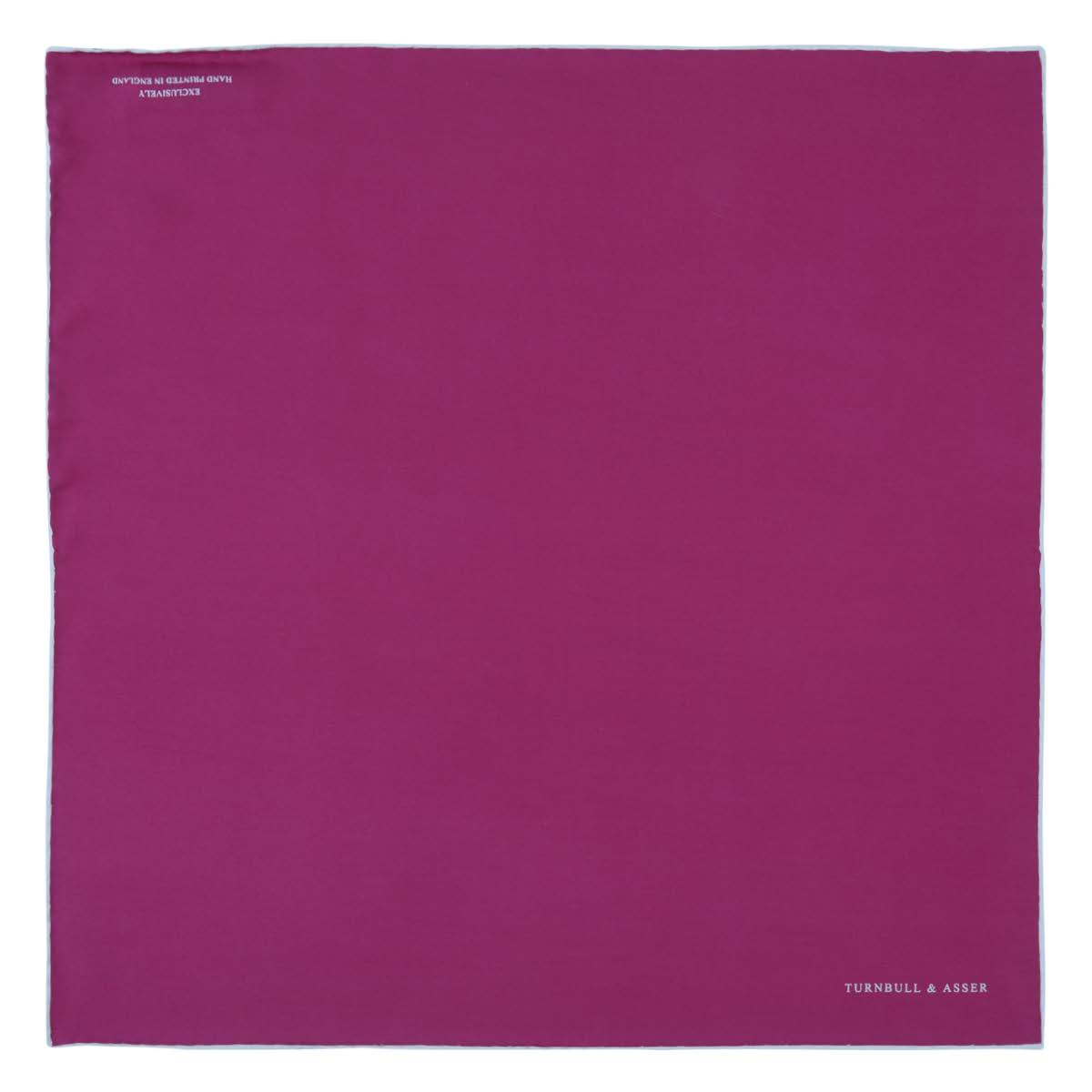 View 2 of product The Fuchsia and White Piped Silk Pocket Square by Turnbull & Asser features white edges and the brand’s name printed in white in the bottom right corner—a timeless men’s accessory.