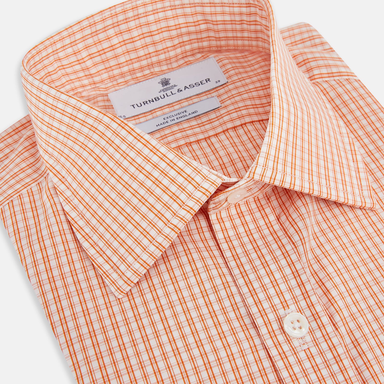 View 2 of product The Turnbull & Asser Orange Micro Check Mayfair Shirt, a long-sleeve button-up with a classic T&A collar and white-orange micro check pattern, is shown neatly laid flat on a white background.