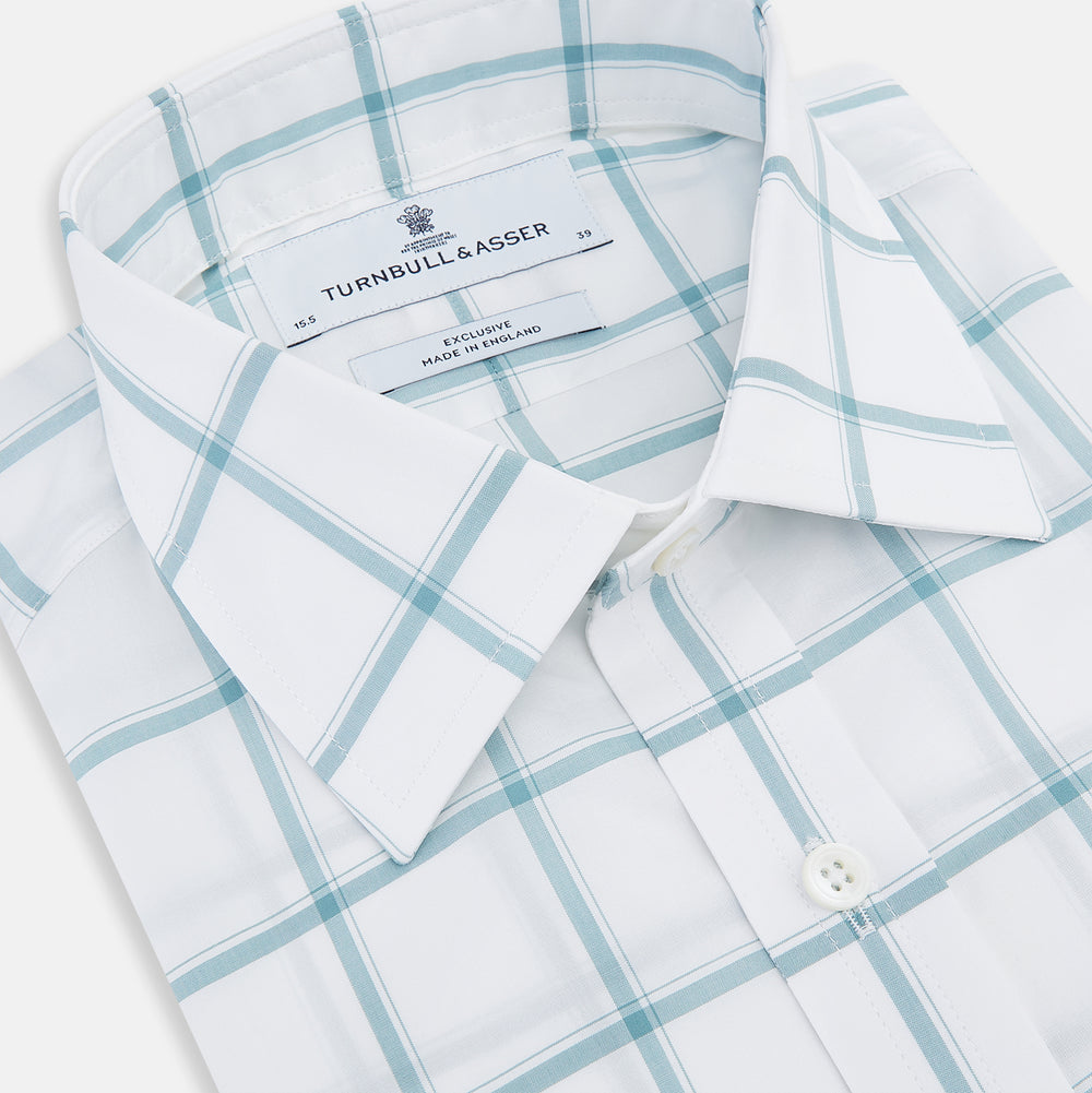 The Turnbull & Asser Sage Grid Check Mayfair Shirt is a white, long-sleeve shirt made from Italian cotton with a light blue and sage grid pattern, shown neatly laid flat on a plain, light background.