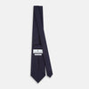 View 4 of product The Turnbull & Asser Navy and Grey Circle Silk Tie, featuring a refined pattern of evenly spaced circles, is elegantly displayed rolled up on a white background—an excellent option for modern office wear.