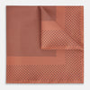 View 1 of product The Turnbull & Asser Blush Dot Silk Pocket Square features a rust hue with black polka dots, a bordered design, and hand-rolled edges, shown folded against a white background.