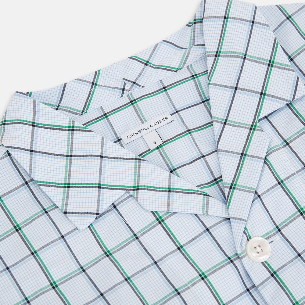 The Turnbull & Asser Green and Blue Check Pyjama Shirt features long sleeves and a button-up design on a white base, offering elegant loungewear style. Shown laid flat against a white background.