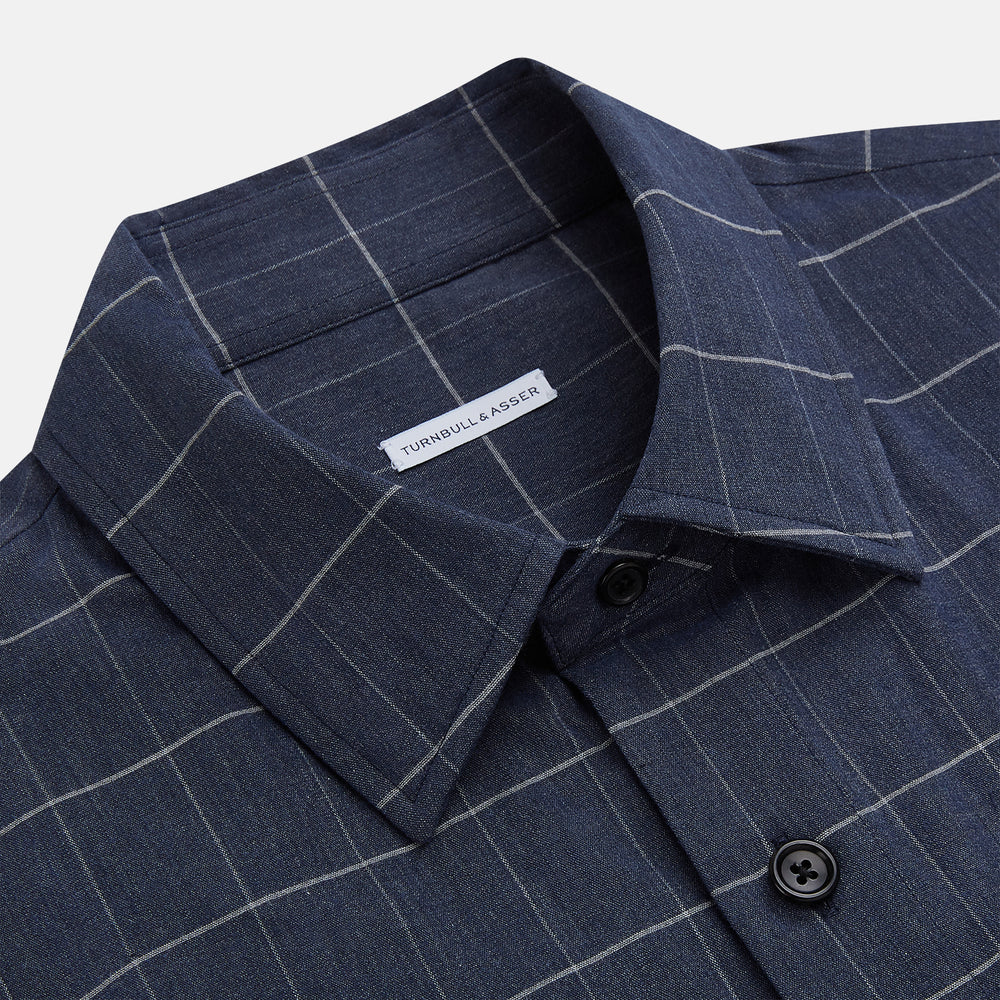 The Turnbull & Asser Royal Blue Check Hampstead Overshirt features a white windowpane pattern, long sleeves, two front pockets, and a chest pocket, displayed on a plain white background for an elegant classic look.