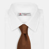 View 2 of product The Turnbull & Asser Plain Lace Jacquard Earth Tie, an essential brown wardrobe accessory, is shown rolled up against a plain white background.
