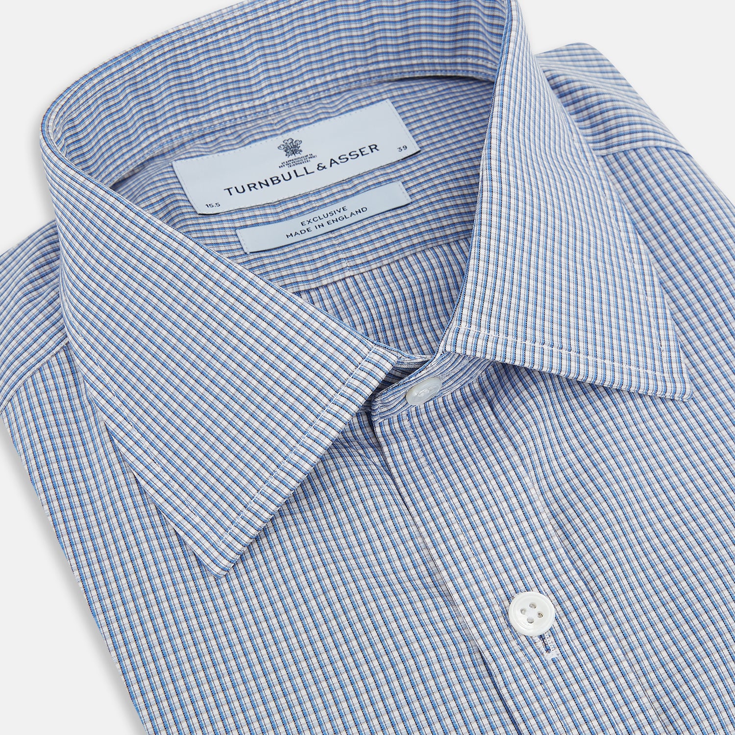 View 2 of product The Turnbull & Asser Pale Blue Micro Graph Check Mayfair Shirt features a small blue and white check pattern, classic T&A collar, white buttons, and buttoned cuffs. Presented on a plain white background.