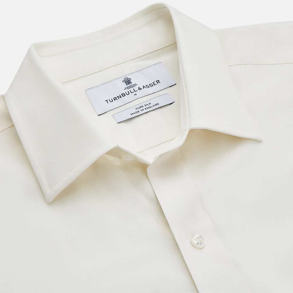 The Turnbull & Asser Cream Silk Weekend Fit Fairlight Shirt is a classic, soft-touch long-sleeve shirt with a collar, button-down front, and buttoned cuffs, shown laid flat on a plain white background.