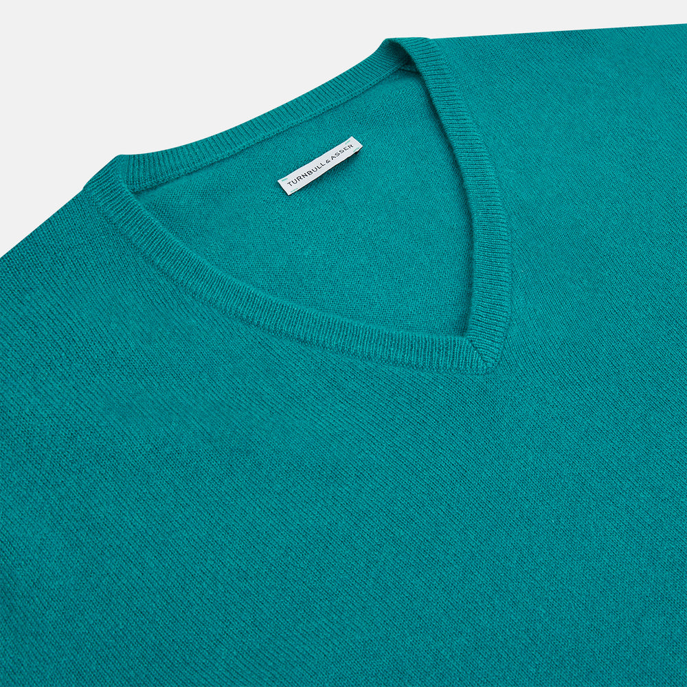 The Turnbull & Asser Turquoise Cashmere V-neck Jumper features long sleeves with ribbed cuffs and hem, displayed on a plain white background—a chic knitwear addition.
