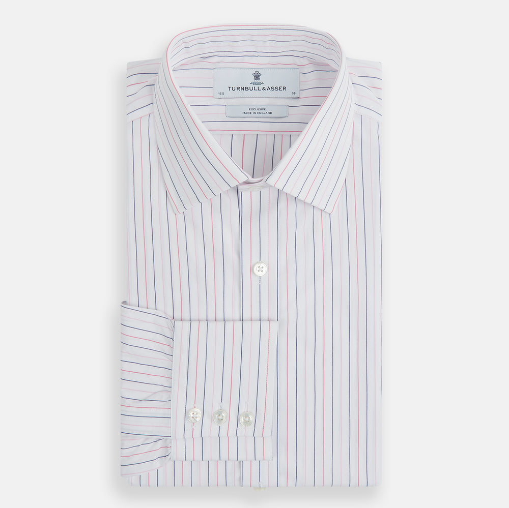 The Turnbull & Asser Pink and Blue Wide Pinstripe Mayfair Shirt features long sleeves, T&A collar, button-down front, and buttoned cuffs. It has bold pink and blue pinstripes on white and is laid flat on a white surface.