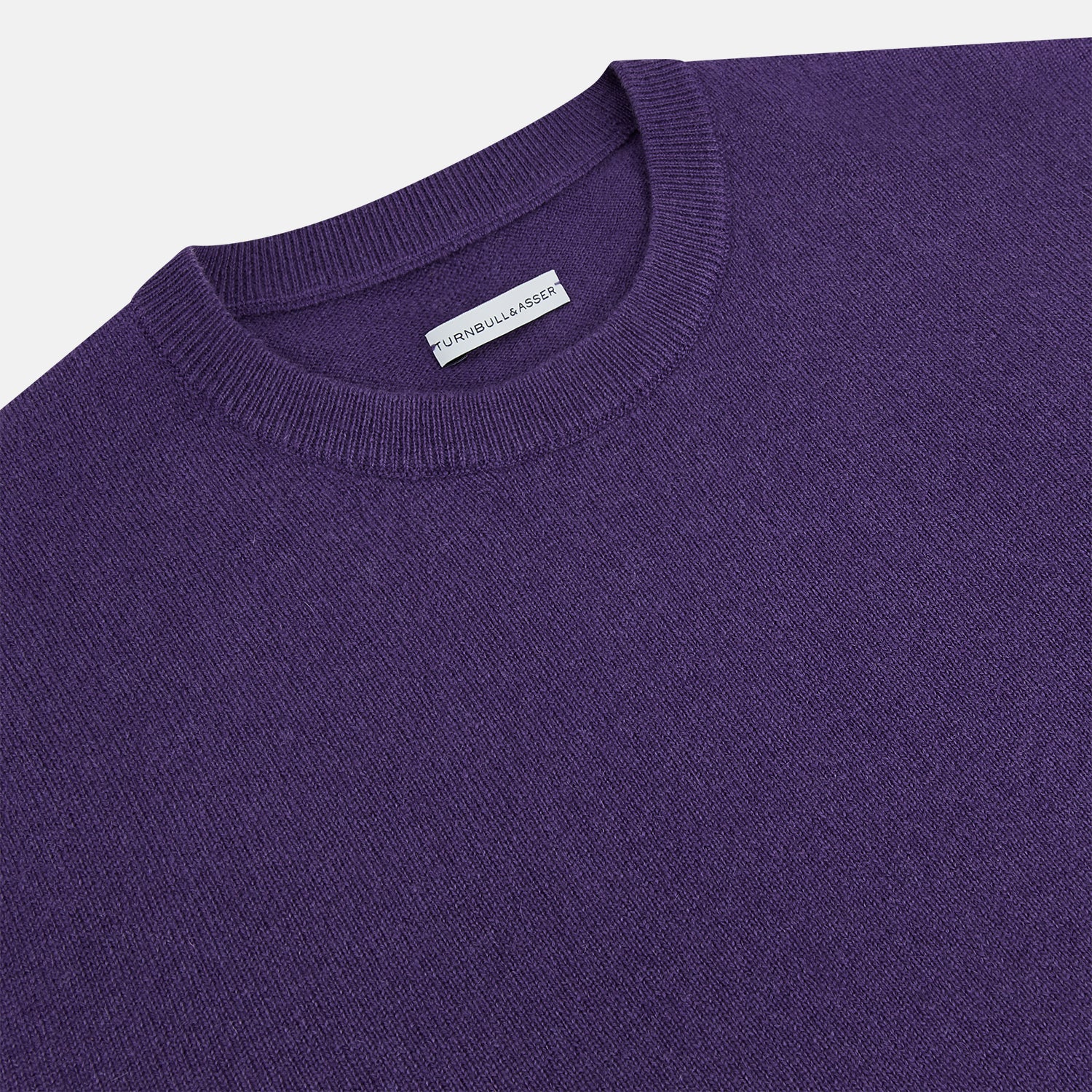 View 2 of product The Turnbull & Asser Purple Cashmere Round Neck Jumper features long sleeves, ribbed cuffs, hem, and collar for an elegant silhouette. This versatile knitwear piece is shown against a white background.