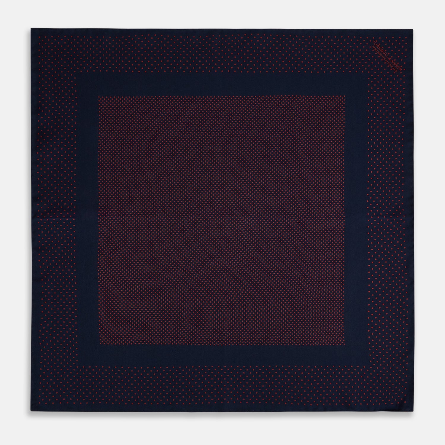 View 4 of product The Turnbull & Asser Navy and Red Dot Silk Pocket Square features a dark navy blue base with small red polka dots on the border and inner pattern, all handmade and neatly folded.