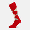 View 1 of product Mid-length orange wool socks by Turnbull & Asser, featuring a classic check pattern in orange, beige, and gray, reminiscent of timeless wool socks, displayed on a plain light background.