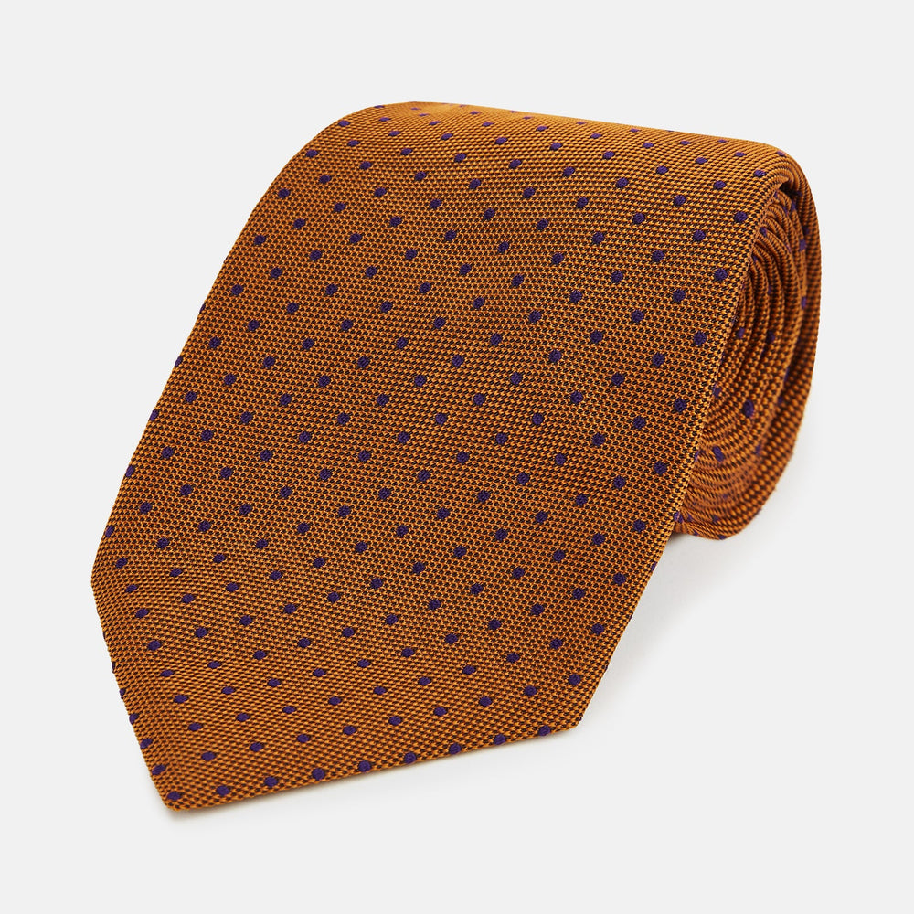 The Turnbull & Asser Purple and Orange Micro Dot Silk Tie, featuring a vibrant polka dot pattern, makes a bold men's accessory and is shown rolled up on a white background.