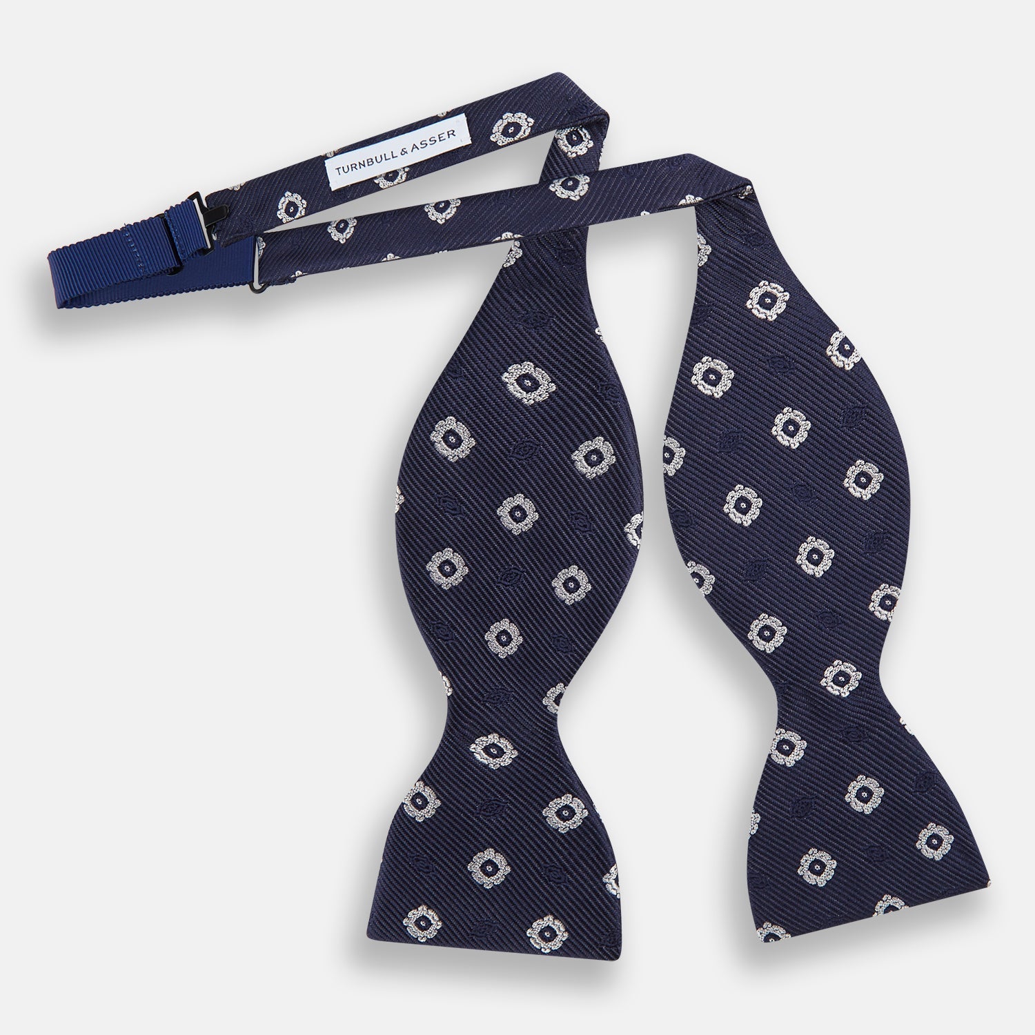 View 2 of product The Navy and White Motif Silk Bow Tie by Turnbull & Asser features a geometric floral pattern, adding refined elegance to formalwear. Shown on a plain white background.