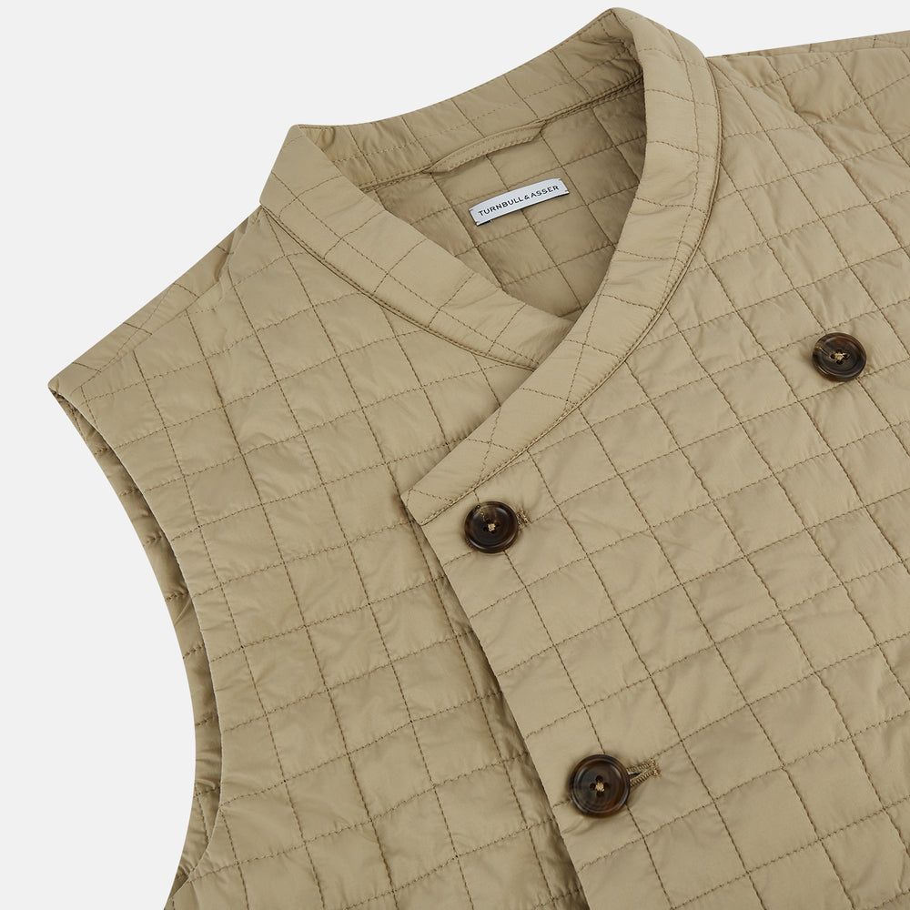The Turnbull & Asser Sand Double-Breasted Quilted Gilet features a sleeveless design, brown buttons, slanted chest pocket, and two zippered side pockets—perfect for modern layered dressing. Shown on a plain white background.