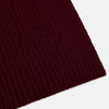 View 2 of product The Burgundy Rib-Knit Cashmere Scarf by Turnbull & Asser is crossed at the center and set against a plain light gray background—an elegant, luxurious winter accessory.