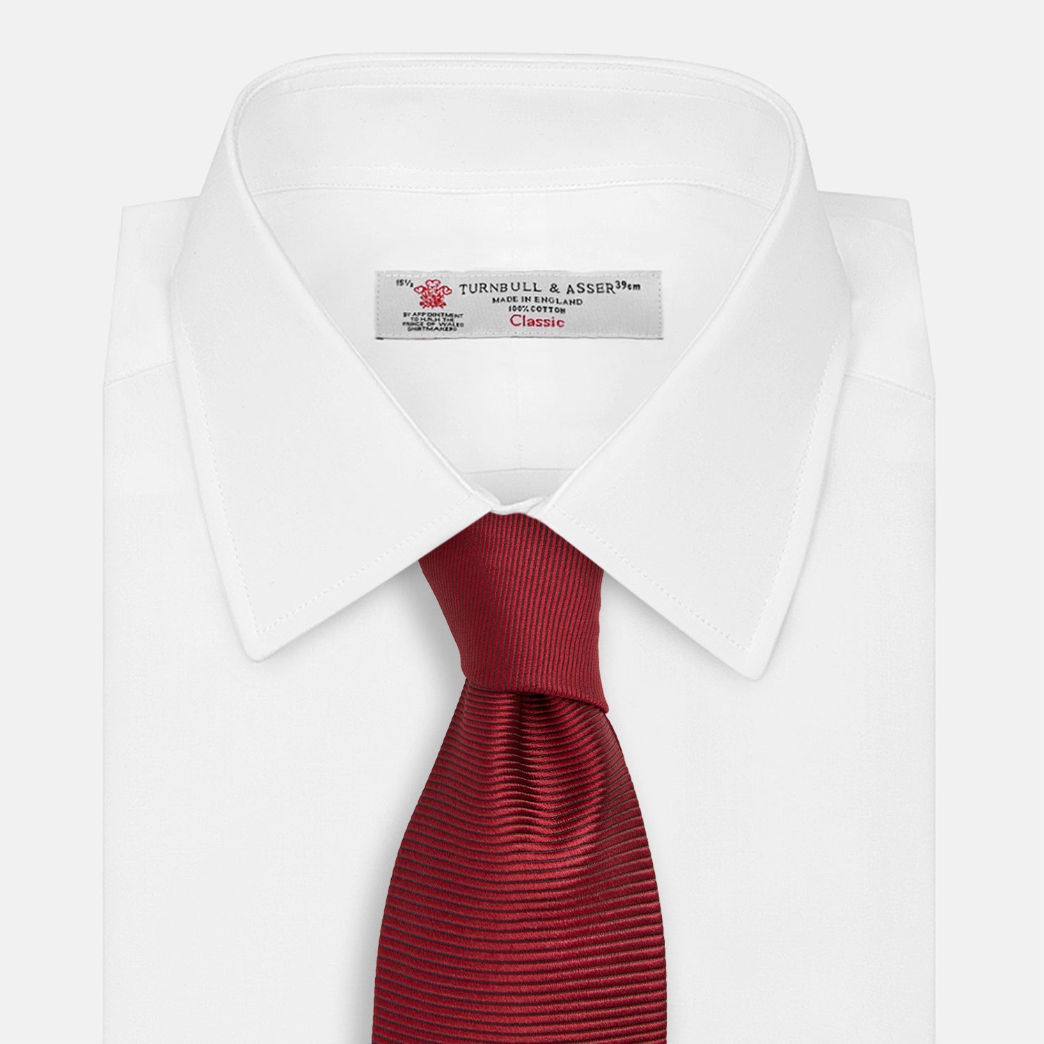 View 2 of product A close-up of the Turnbull & Asser HORIZONTAL TWILL BURGUNDY TIE, a textured men's accessory, rolled up and displayed on a plain white background.