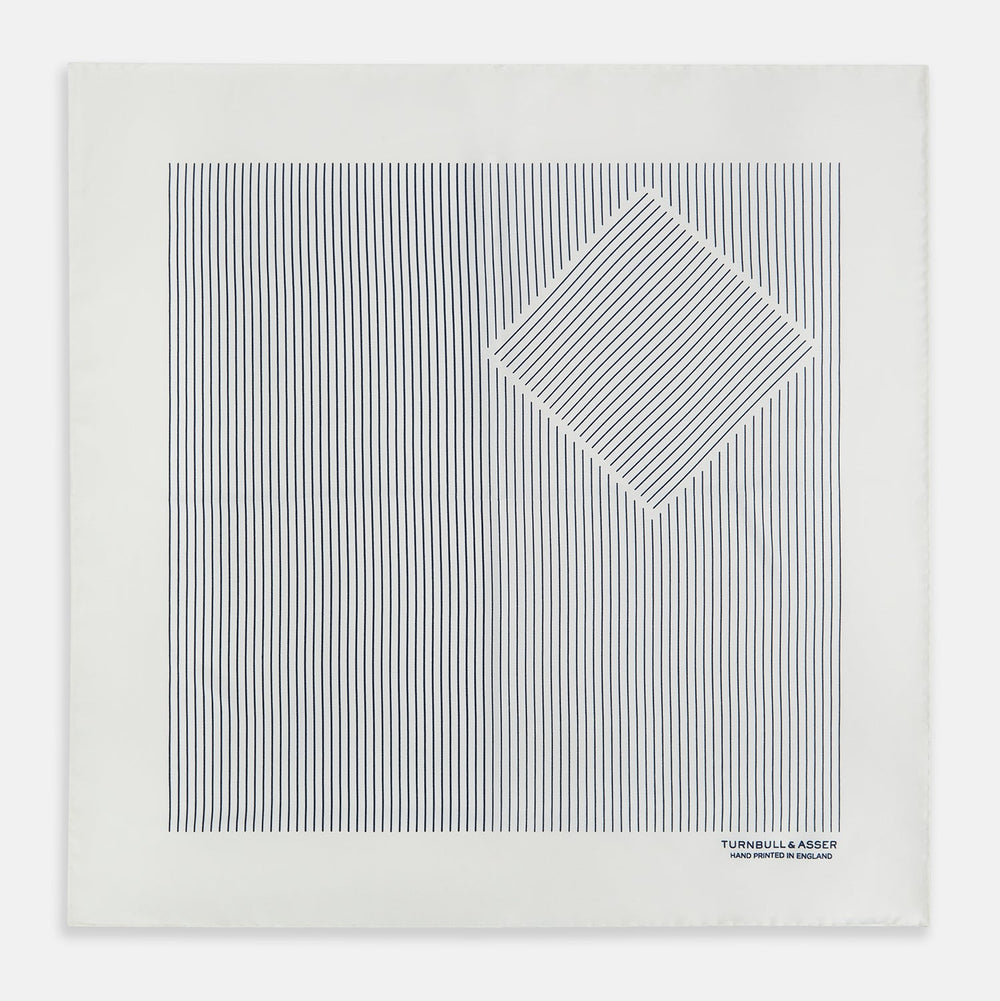 The White Stripe Silk Pocket Square by Turnbull & Asser features vertical navy pinstripes and “TURNBULL & ASSER HAND PRINTED IN ENGLAND” in blue at the lower right, with one corner neatly folded for a classic British look.