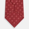 View 3 of product The Turnbull & Asser Red Medallion Silk Tie features a repeating white geometric medallion motif on vibrant red silk, shown against a plain white background.