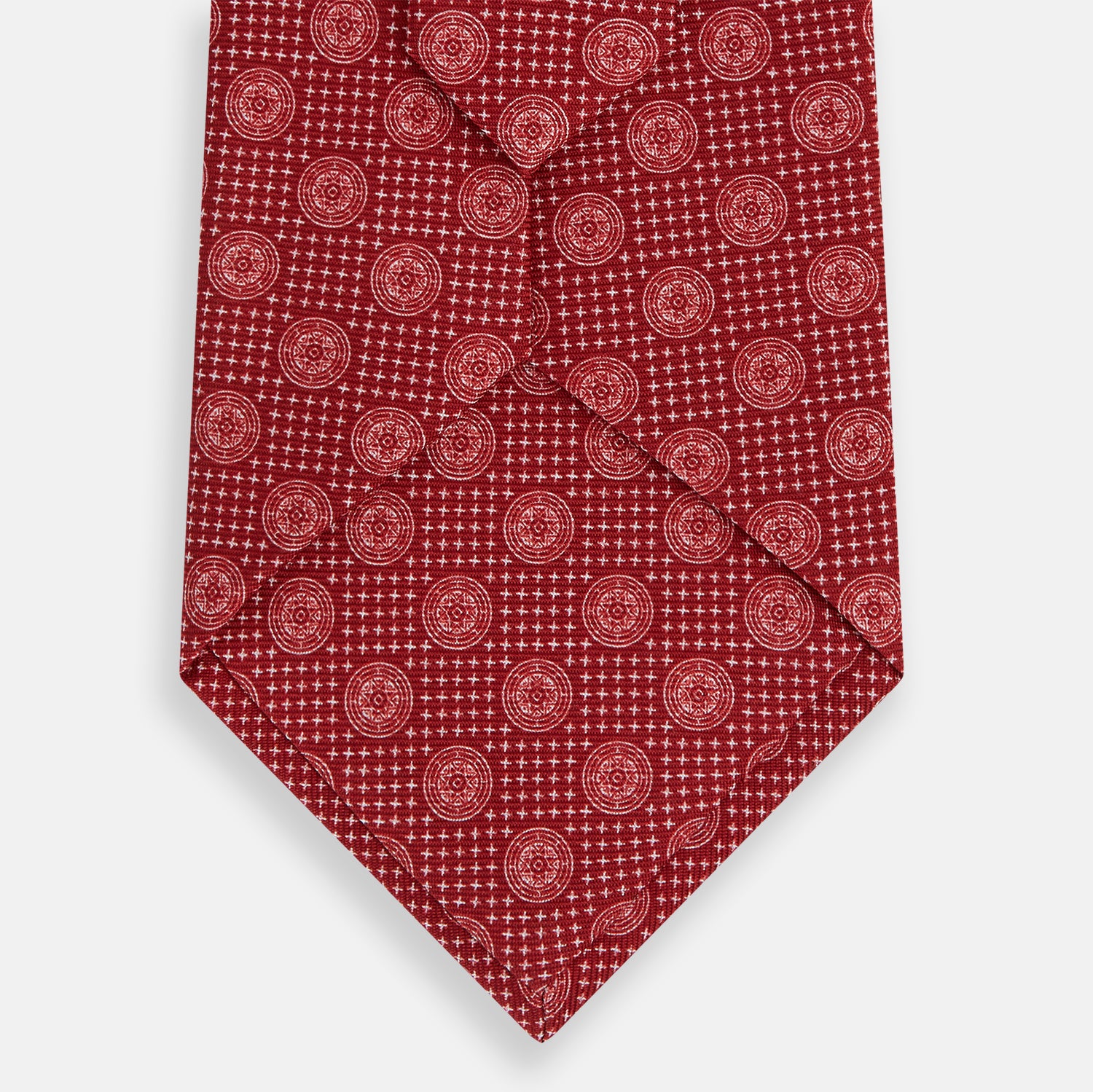 View 3 of product The Turnbull & Asser Red Medallion Silk Tie features a repeating white geometric medallion motif on vibrant red silk, shown against a plain white background.