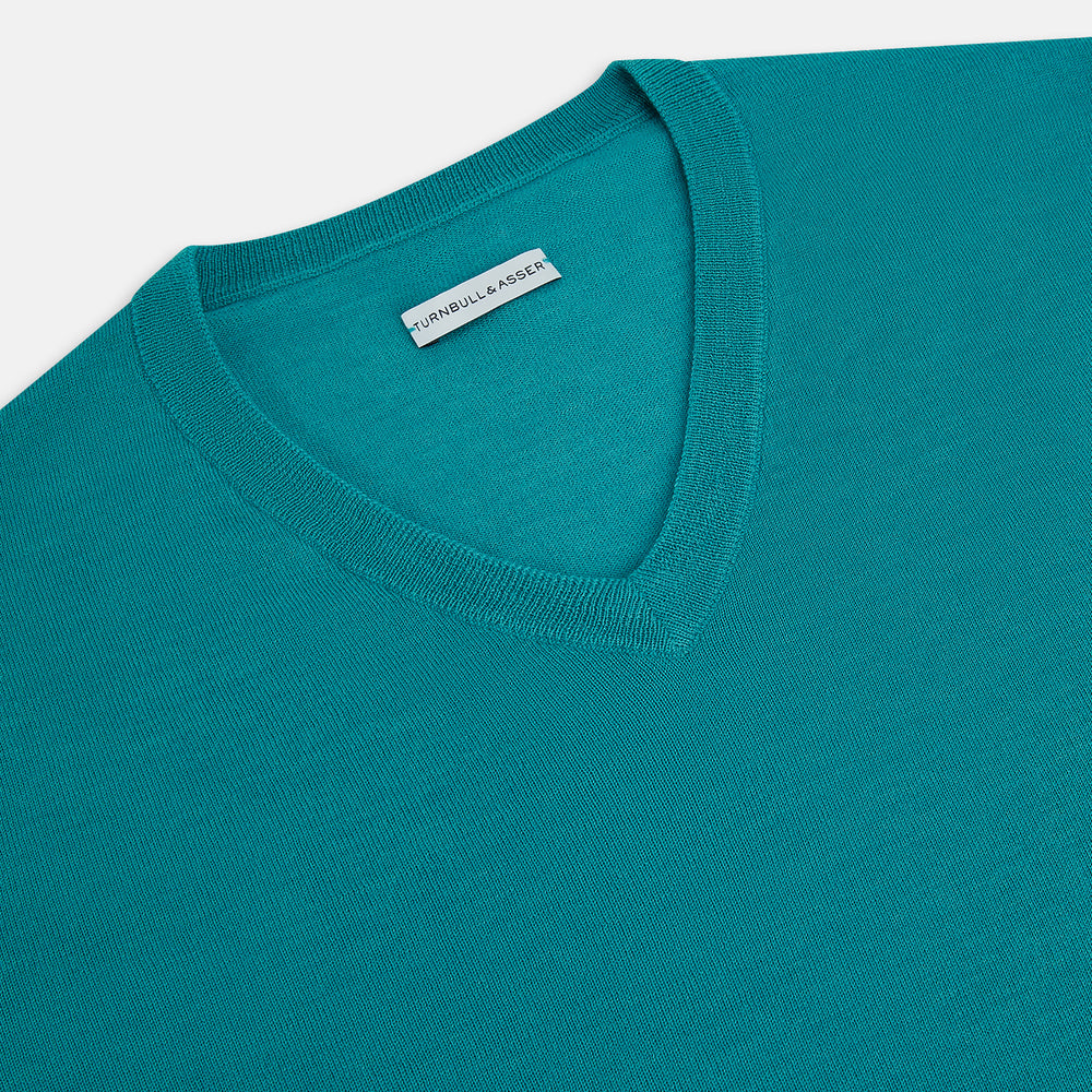 The Turnbull & Asser Turquoise Fine Merino V-Neck Jumper features long sleeves, ribbed cuffs and waistband, shown on a white background—a timeless choice for classic knitwear enthusiasts.