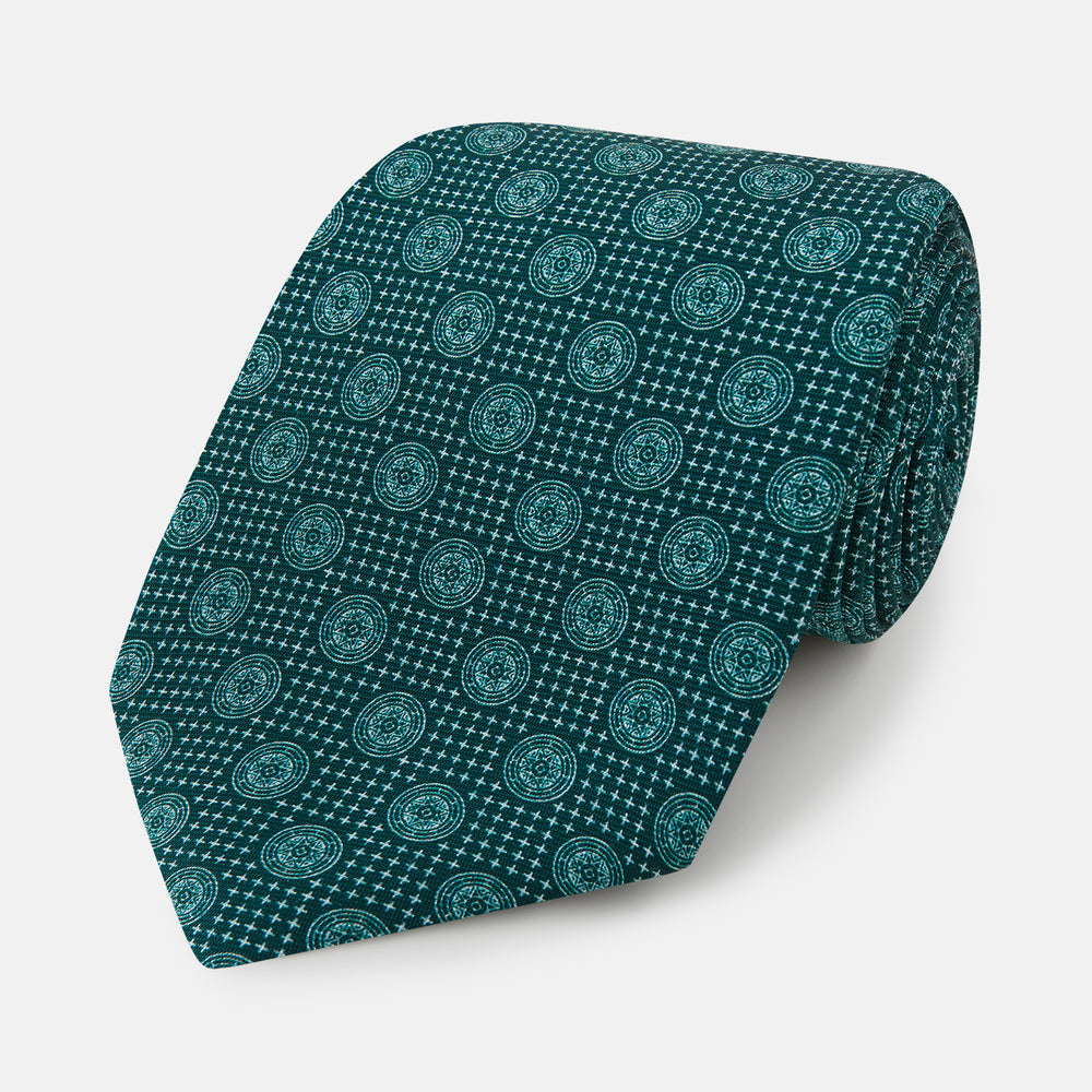 The Forest Green Medallion Printed Silk Tie by Turnbull & Asser features a repeating medallion pattern in lighter green tones, crafted from English silk and shown rolled up on a plain white background.