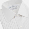 View 2 of product The Turnbull & Asser White Pleated Cotton Dress Shirt features a T&A collar, pleated front, double cuffs, and a button-down front, shown laid flat against a white background.