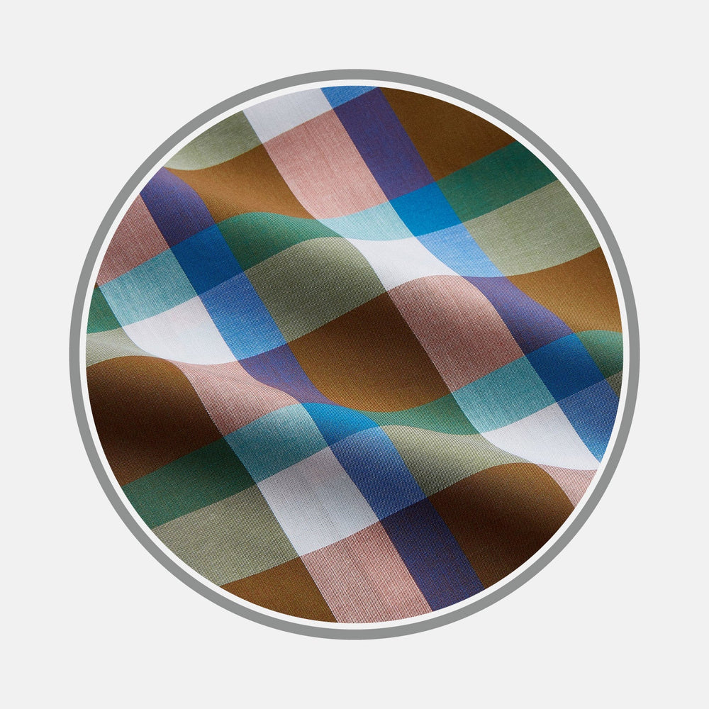 A close-up of Turnbull & Asser’s NEW BESPOKE FABRIC 1301 28 shows its multicolored plaid texture—blue, green, brown, pink, and white—ideal for custom or bespoke shirts, displayed in a circular frame on a white background.