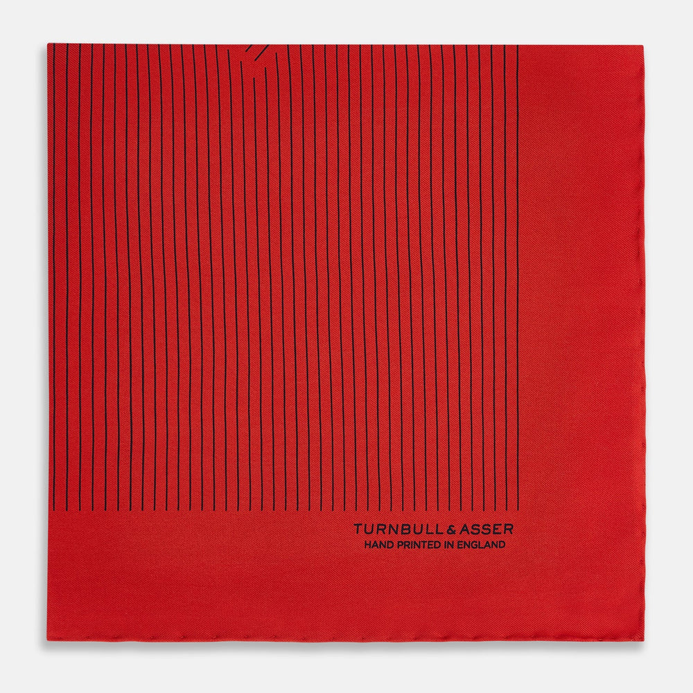 The Red Stripe Silk Pocket Square by Turnbull & Asser features thin black vertical lines and the brand signature in black on one corner, with a neatly folded edge for a touch of classic British style.